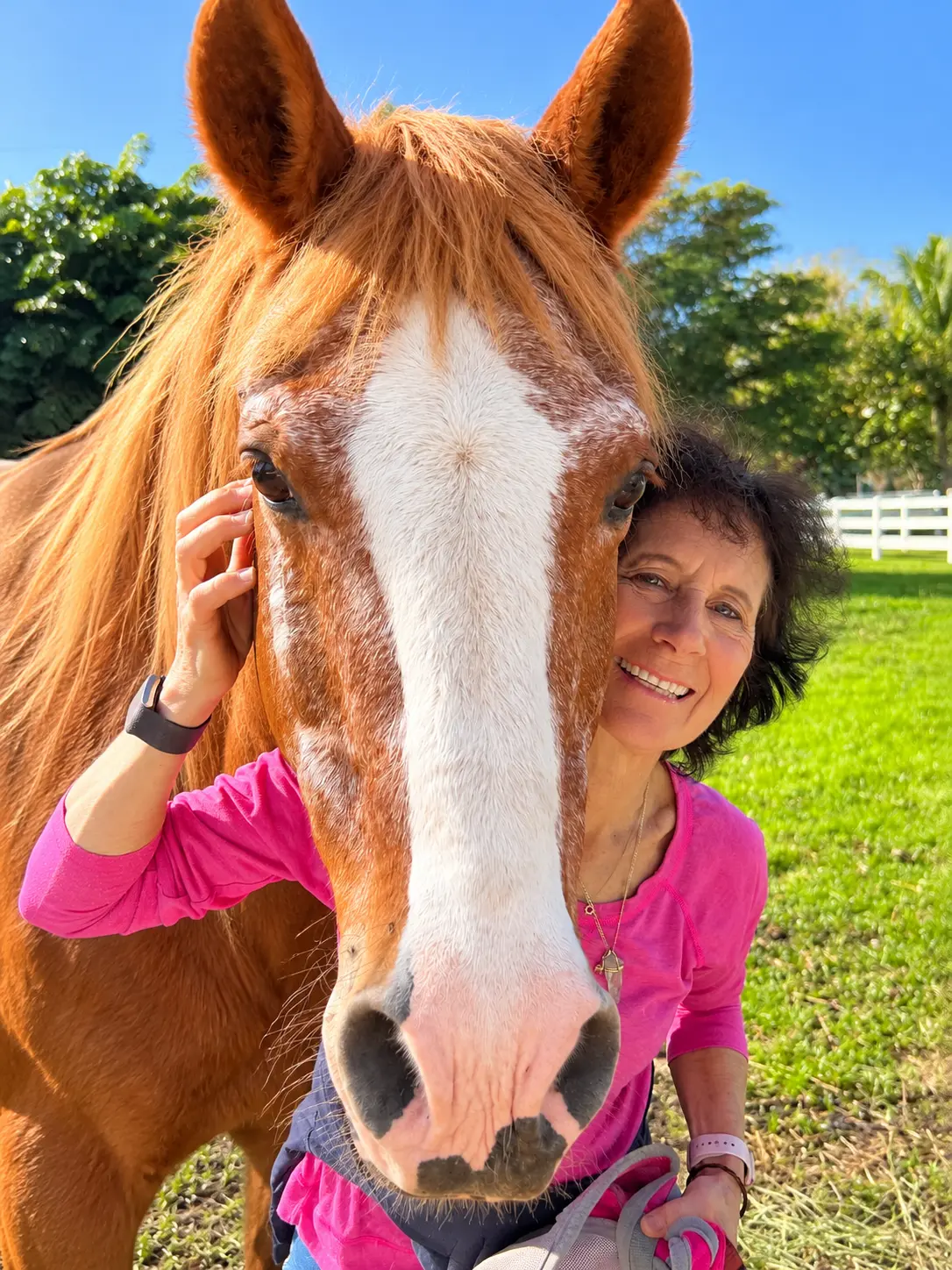 Nikki Kagan in a pink shirt beside a chestnut horse