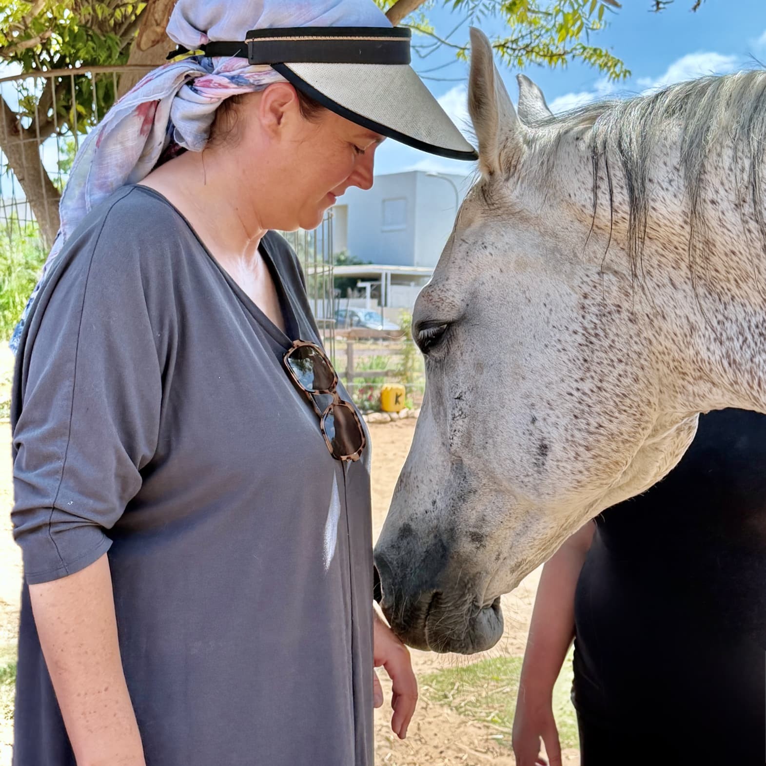 A quiet one-to-one moment as a woman stands face to face with the white horse